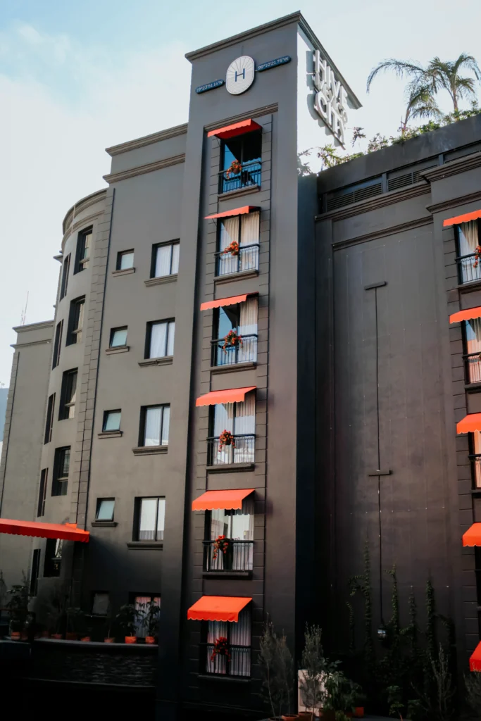 Fachada del Hotel Hive CDMX desde lejos durante el atardecer."